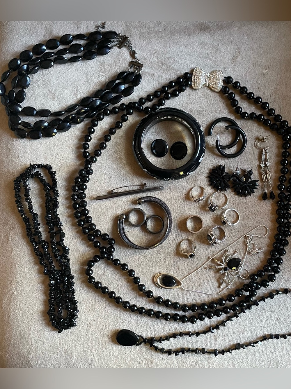 Bundle of black tone fashion jewelry in a vintage tin box .